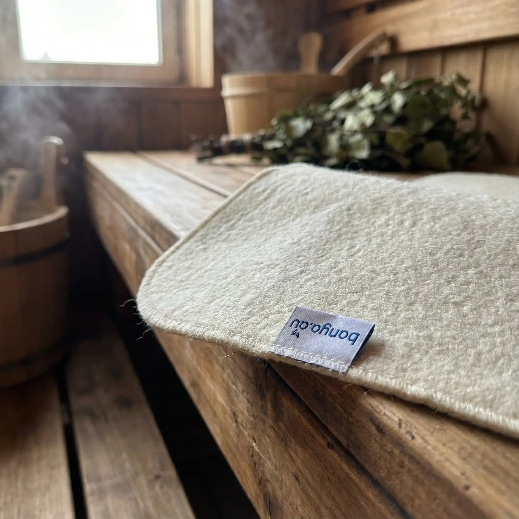 Natural wool sauna mat on a traditional sauna bench designed for comfort, insulation and hygiene