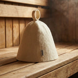 Traditional wool sauna hat on a wooden sauna bench with steam in the background